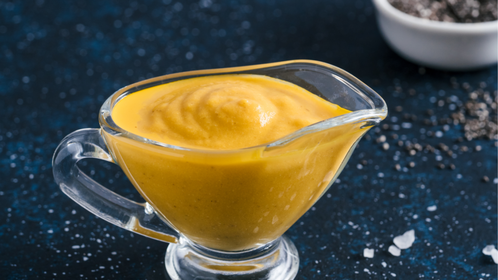a glass gravy boat with yellow liquid in it